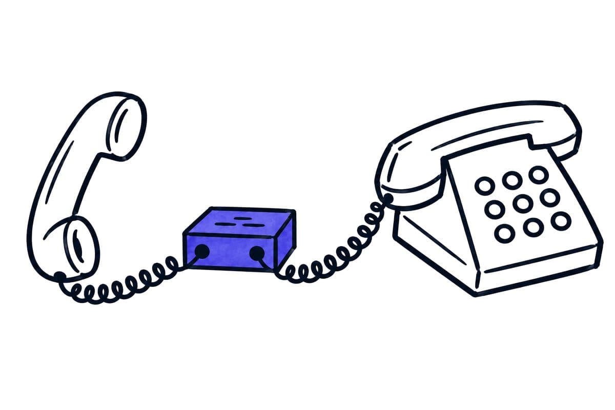 Illustration: a telephone receiver and a desk phone connected through a small switch box